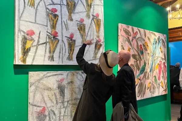 a couple of people standing next to a wall with paintings on it